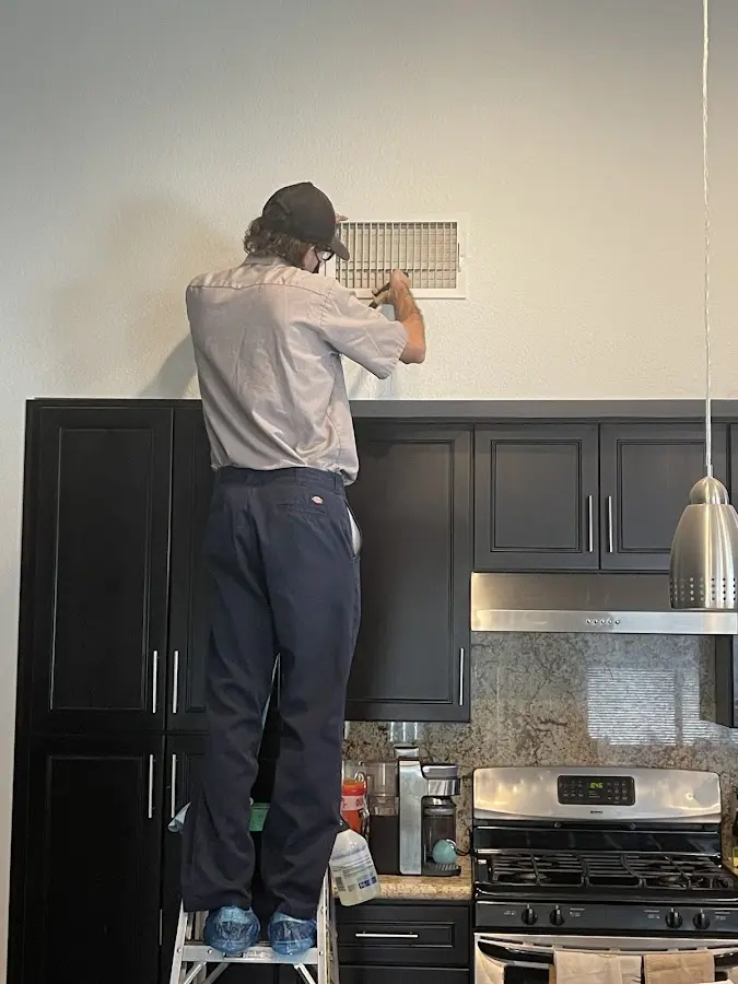 Technician inspecting an air vent during HVAC service in Gladewater